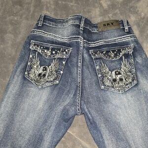 SkyDistressed Blue Jeans with Embellished Winged Skull Pockets